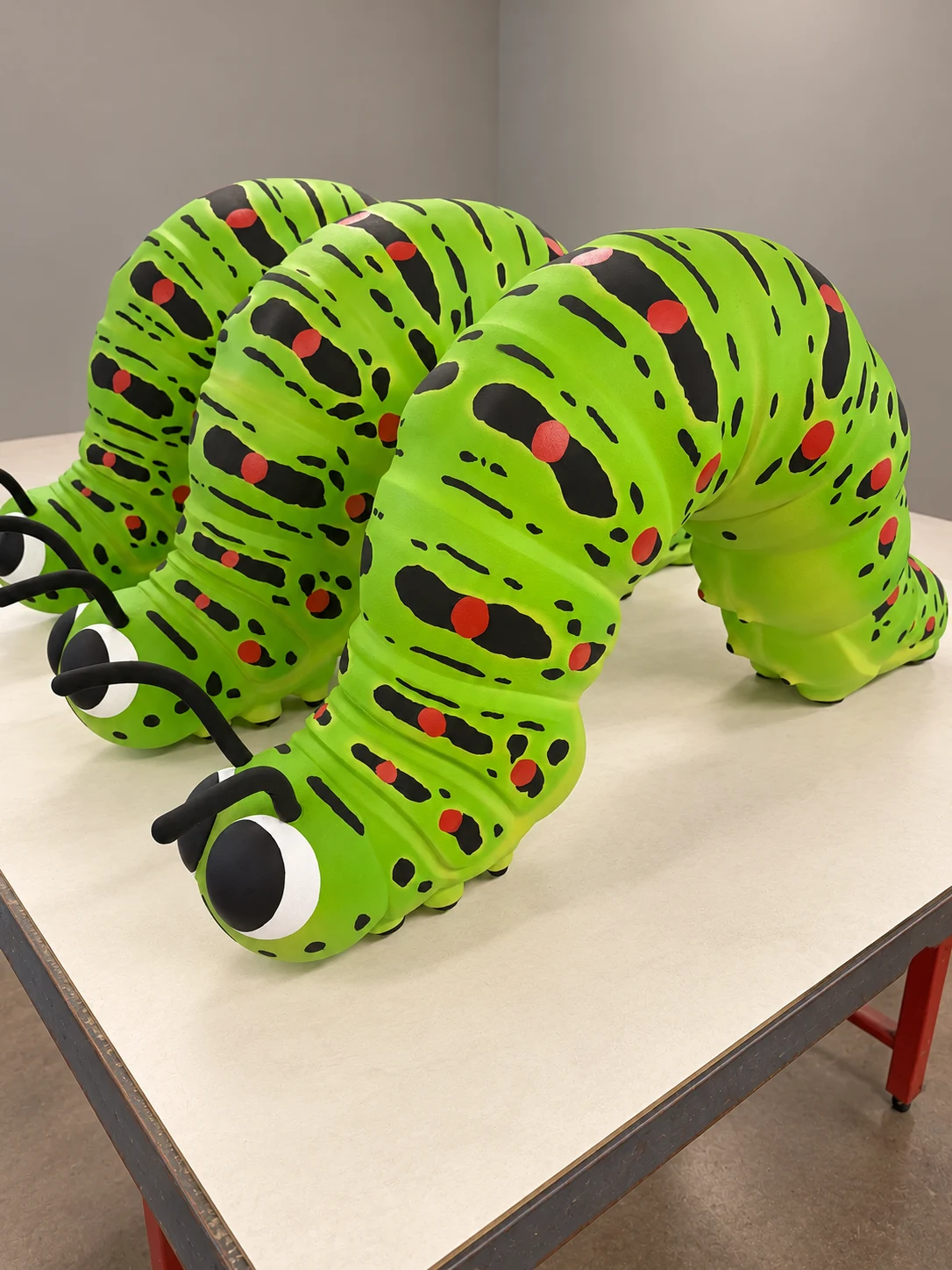 Trois sculptures de chenilles vertes peintes — arrière-plan retouché